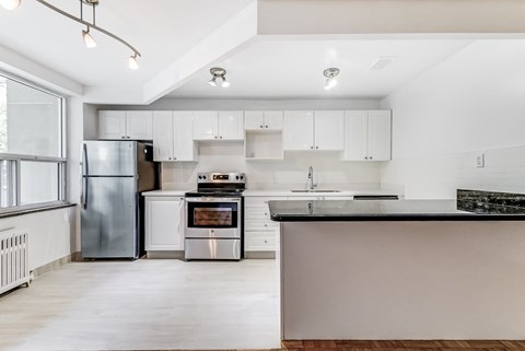 an empty kitchen with white cabinets and stainless steel appliances